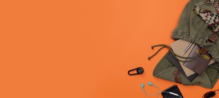 Top view mockup of Traveler's accessories with passport, books of travel plan, smart phone and backpack long banner isolated orange background with empty space,Tropical travel conceptの写真素材