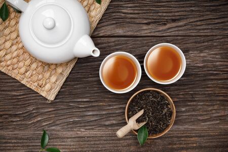 Tea cup with teapot, organic green tea leaves and dried herbs on the wooden desk empty space creative flat lay, Organic product from the nature for healthy with traditional styleの写真素材