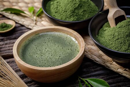 Japanese organic matcha green tea powder in bowl with wire whisk and green tea leaf on wooden background, Organic product from the nature for healthy with traditional styleの写真素材