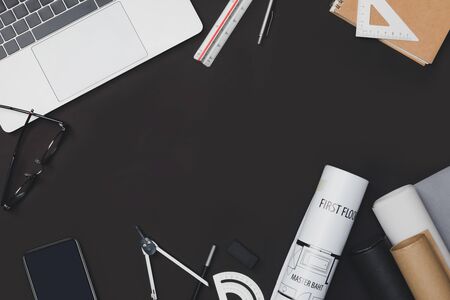 Creative flat lay of architects black table with roll blueprints, architectural project plan, engineering tools, office supplies and laptop computer, Workspace for new designer conceptの写真素材