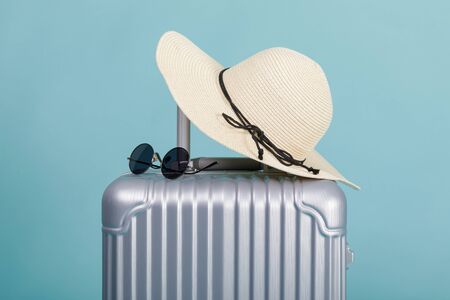 Travel Baggage with hat and sunglasses isolated on blue background with copy space, Travel concept backgroundの写真素材