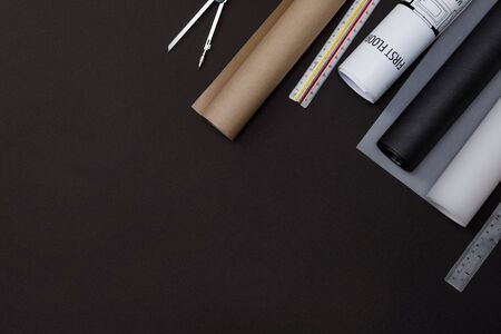 Creative flat lay of architects black table with roll blueprints, architectural project plan,...