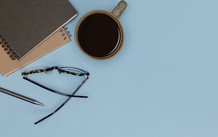 Creative flat lay of office supplies mockup with hot coffee cup, glasses, books and accessories isolated on blue long banner background, Top view with copy space, Workspace for freelancerの写真素材
