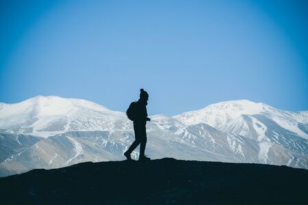 Silhouette of woman hiker stands on the rock in the beautiful mountains view of snowy Tso Moriri Lake in Leh Ladakh india, success conceptの写真素材