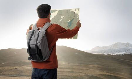 A young traveler man on the top of mountain with backpack and look searching direction on location map, Adventure and travel in the concept, Travelling tour in Asia:Leh Ladakh,indiaの写真素材