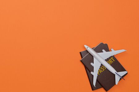 Creative flatlay of Traveler's accessories with passport and airplane toy isolated orange background with empty space,Tropical travel conceptの写真素材