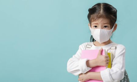 Asian little child girl wearing respirator mask for stop coronavirus outbreak, New virus Covid-19 concept, Empty space isolated on blue long bannerの写真素材