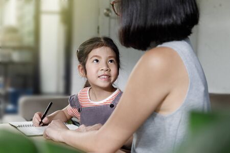 Businesswoman mother woman with a child girl working on the desk in the home, Working from home lifestyle concept, Quarantine isolation during the Coronavirus (COVID-19) health crisisの写真素材