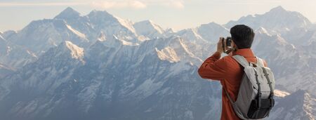 Travelling tourist with his backpack on the top of iceberg mountain with backpack in the nature and take a photo with digital camera the beauty of landscape, Adventure and travel in the mountains region conceptの写真素材