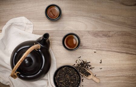 Tea cup with teapot, organic green tea leaves and dried herbs on the wooden desk empty space creative flat lay, Organic product from the nature for healthy with traditional styleの写真素材