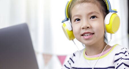 Asian little child girl learning at home with laptop computer using meeting online app, Quarantine isolation during the Coronavirus (COVID-19) health care, online education conceptの写真素材