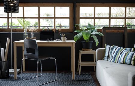 Modern home office creative space perfect for working from home lifestyle with laptop on the desk and sofa in the living room, Quarantine isolation during the Coronavirus (COVID-19) health crisisの写真素材