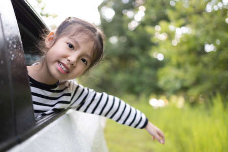 Smiling little Asian girl in car going to summer travel trip.の写真素材