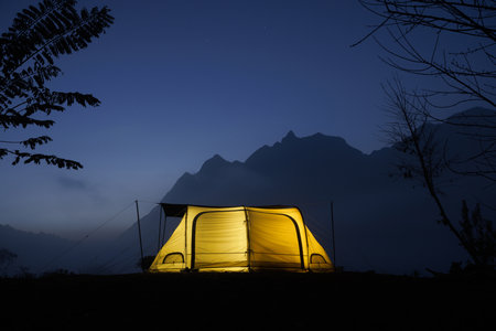 Camp and tent in the night in front of the mountains with cloud in natural park, Tourism conceptの写真素材