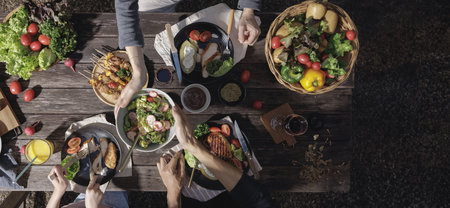 A dinner table with many grill steaks and vegetables salad with father mother and daughter at outdoor garden, Top view, Conceptual of party family healthyの写真素材