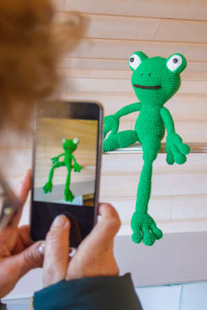 Amigurumi doll green frog photographed on a white background in various poses.の写真素材