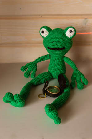 Amigurumi doll frog determines the direction of movement of the compass.の写真素材