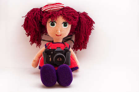 Handmade doll Amigurumi girl sitting. Isolated.