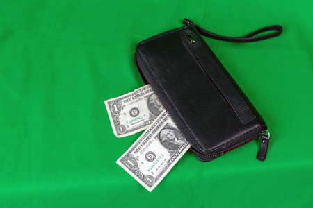 Dollar bills protrude from a black wallet.の写真素材