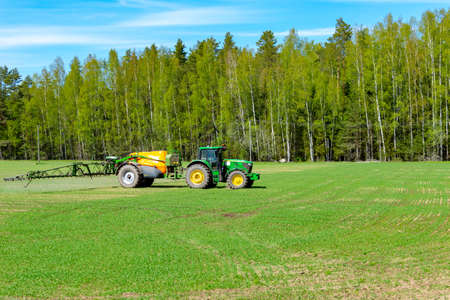 A tractor sprays fertilizer on spring fields.の写真素材