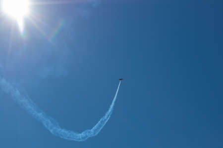 A sports plane makes figures in the sky with a trail.の写真素材