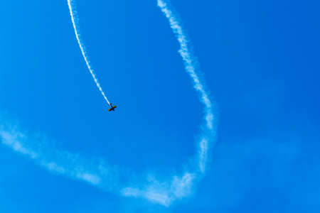 A sports plane makes figures in the sky with a trail.の写真素材