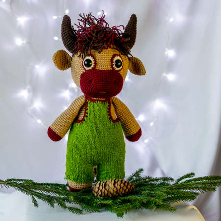 Handmade doll Amigurumi bull. Spruce branch with cones. White background.の写真素材