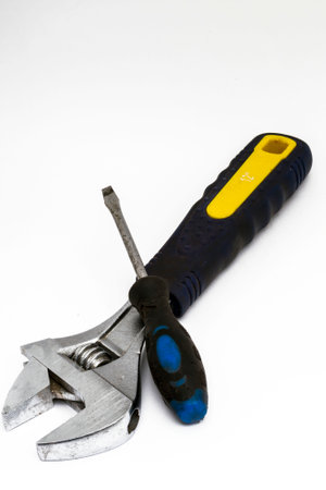 Adjustable wrench and flat head screwdriver lie on white background.
