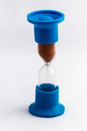 Glass hourglass in a blue frame isolate on white