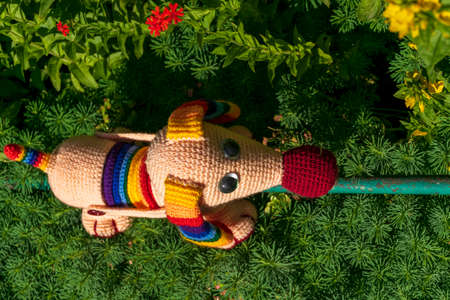 Amigurumi doll dog among flowers in the garden.