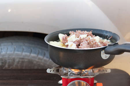 Potatoes with stew is cooked on a camp stove