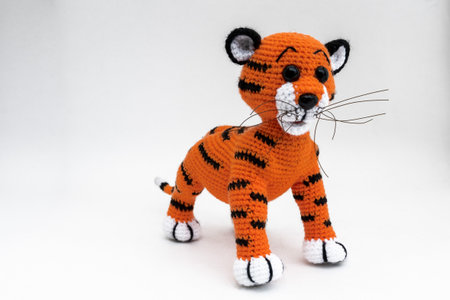 Handmade amigurumi doll tiger cub stands. The background is white. isolate.の写真素材