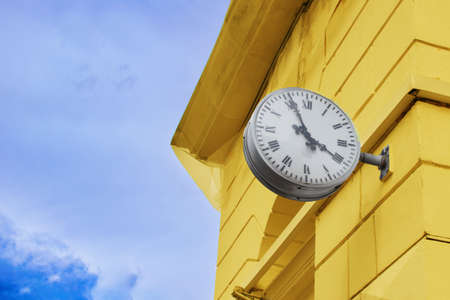 Round clock on the wall of the house with a Roman dialの写真素材