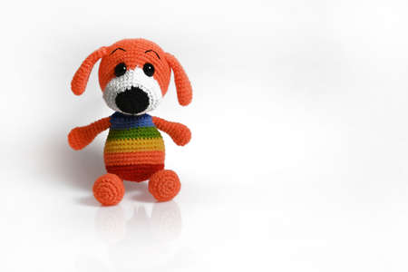 Handmade amigurumi doll rainbow dog sitting. Isolate, copy spaceの写真素材