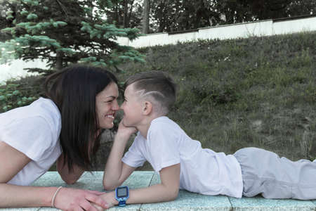 Mom and son lie side by side in the park on a summer day.