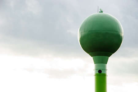 The green water tower against cloudy skyの写真素材