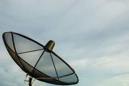 The black satellite dish with cloudy skyの写真素材