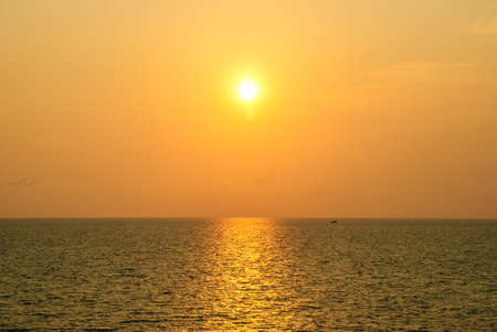 a little boat floats in the sea during sunset timeの写真素材