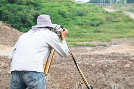 Builder surveyor working with optical equipment level at construction site.の写真素材