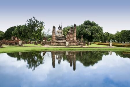 ancient buddha reflected in lake, temple ruins of sukhothai historic park in northern thailandの写真素材