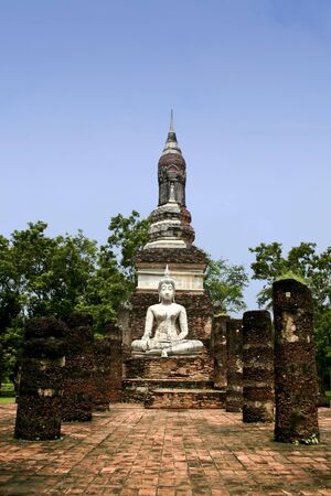 white seated buddha in the temple ruins of the ancient city of sukhothai in thailandの写真素材