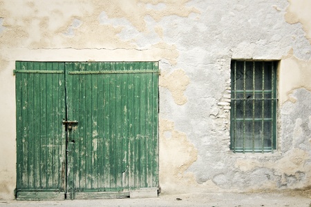 old green wooden door padlocked closed set in crumbling old wall with exposed bricks in the south of franceのeditorial素材