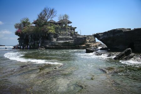 waves crashing around the sea temple of tanah lot built on a rocky outcrop of the coast of bali indonesiaのeditorial素材