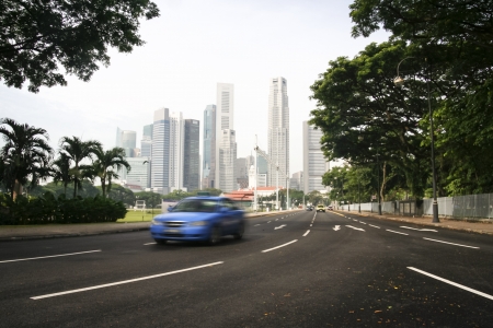 blue taxi cab driving away from city centre financial district of singaporeの写真素材