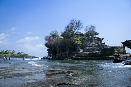 tourists crossing to the landmark sea temple of tanah lot on the coast of bali indonesiaの写真素材