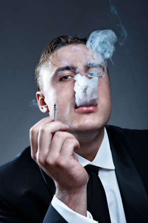 Closeup portrait of smoking handsone young man in suitの写真素材