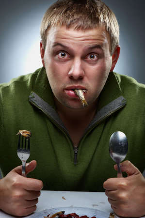 Portrait of hungry man with fish in mouth 