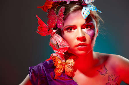 Colorful fashion portrait of attractive young beauty with butterflies in hairsの写真素材