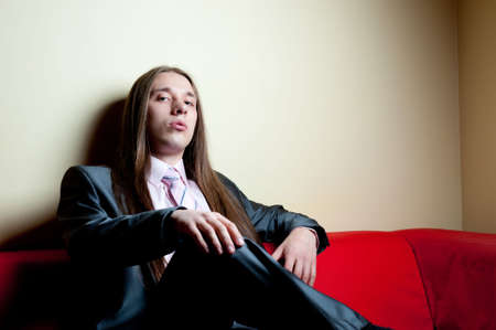 Portrait of longhaired serious man in suit sittingの写真素材