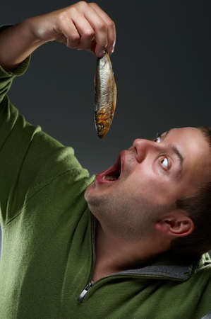 Hungry corpulent man with open mouth staring at a fishの写真素材